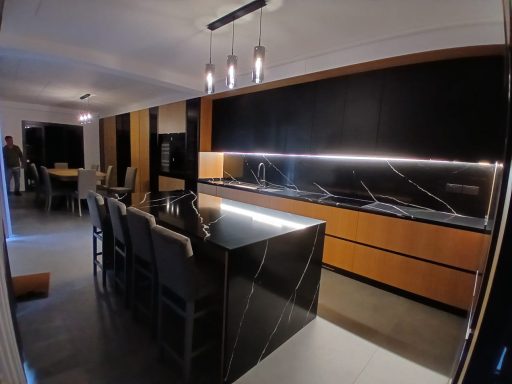 Cucina moderna con isola centrale, piani in granito e illuminazione elegante.