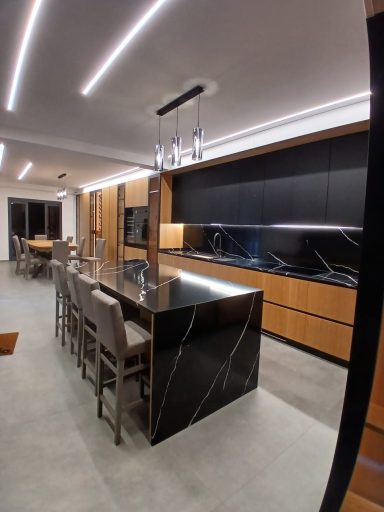 Moderna cucina con isola nera, armadi in legno e illuminazione a LED.