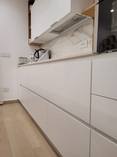 Modern kitchen with white cabinetry and minimalist design, featuring a countertop and appliances.