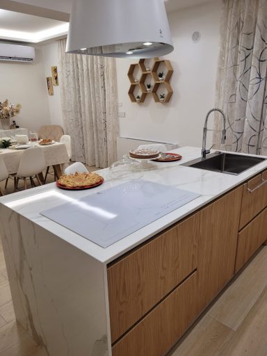 Modern kitchen with a wooden island, sink, and dining area in the background.