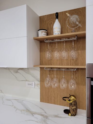 Ripiano in legno con bicchieri appesi, bottiglia e oggetti decorativi. Cucina moderna.